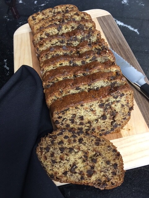 Loaf of sliced banana bread displayed on a cutting board with a knife.